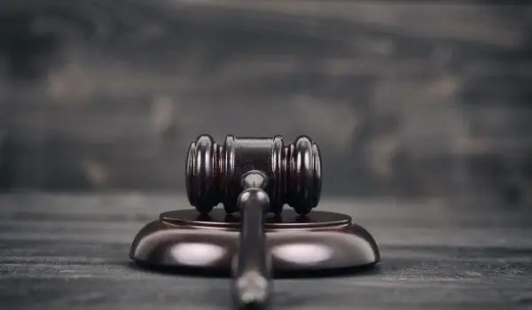 A wooden judge's gavel rests on its sound block on a dark wooden background, symbolizing law and authority.