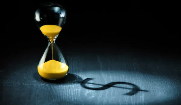 Hourglass projecting a dollar sign as shadow.