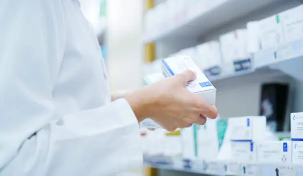 Doctor, hands or shelf with medication at pharmacy for inventory, stock or pharmaceutical service. Closeup, healthcare employee or pharmacist with box or medical product for side effect at drug store