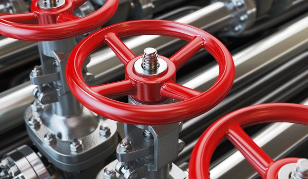Red wheel valves are mounted on an industrial pipeline.