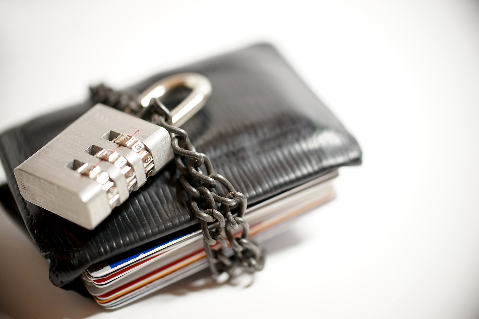A wallet is wrapped with a chain and secured with a combination lock.