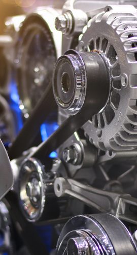 A close-up view of an engine reveals a shiny alternator, various pulleys, and a cooling fan, showcasing the complex mechanical components of a vehicle's power system.