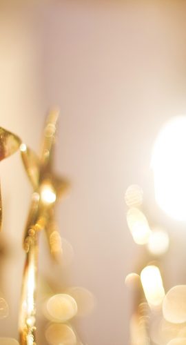Golden star-shaped figures are illuminated by a soft, warm light, creating a festive and cozy atmosphere.