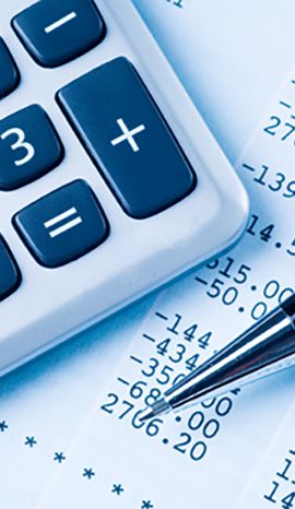 A calculator and a pen lie atop financial documents with numerical data.