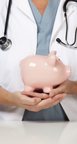 A healthcare professional in a lab coat with a stethoscope around their neck is holding a pink piggy bank.