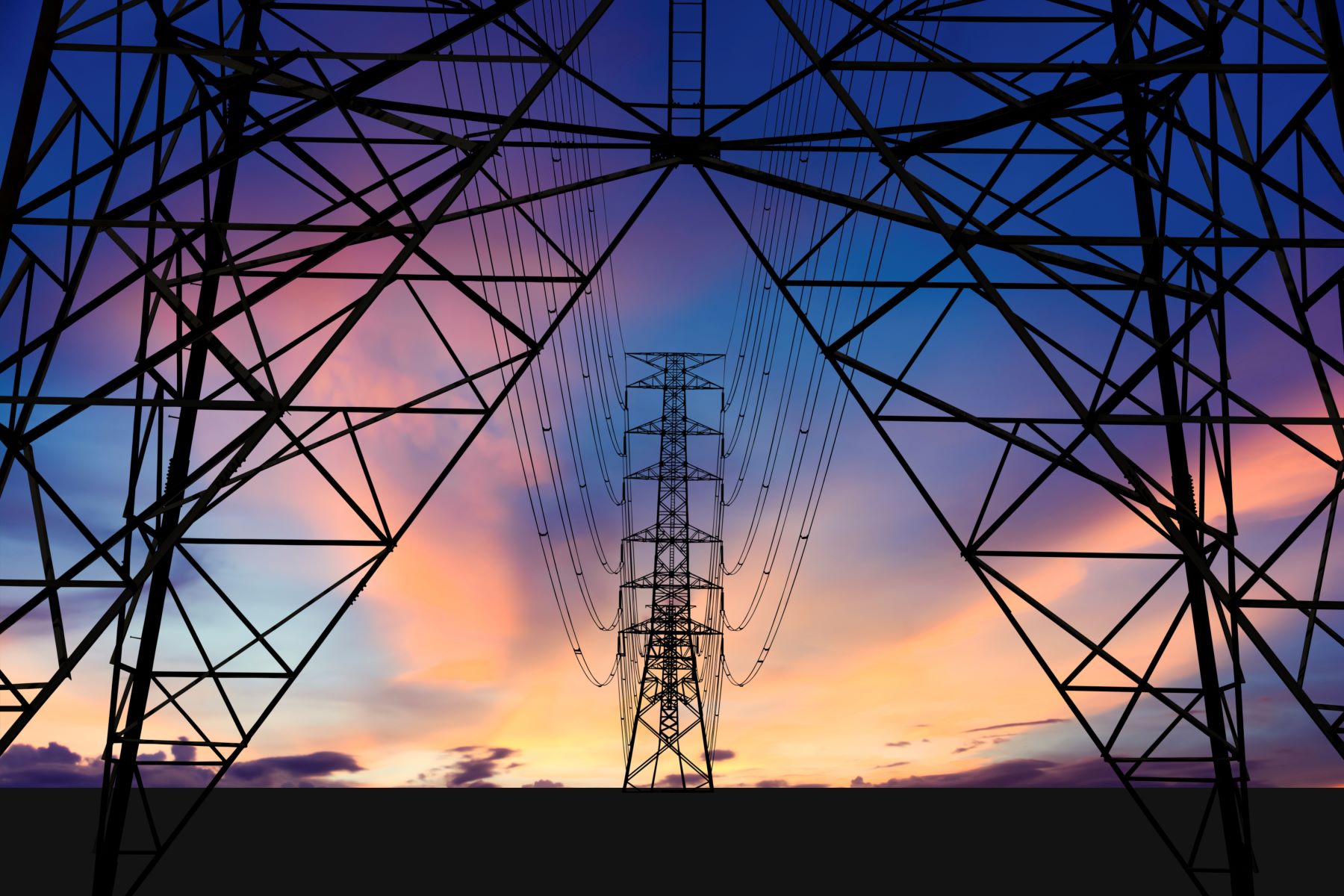 A symmetric view from inside an electricity pylon with a sunset sky in the background.