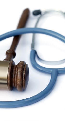 A wooden gavel rests beside a stethoscope, symbolizing the intersection of law and healthcare.
