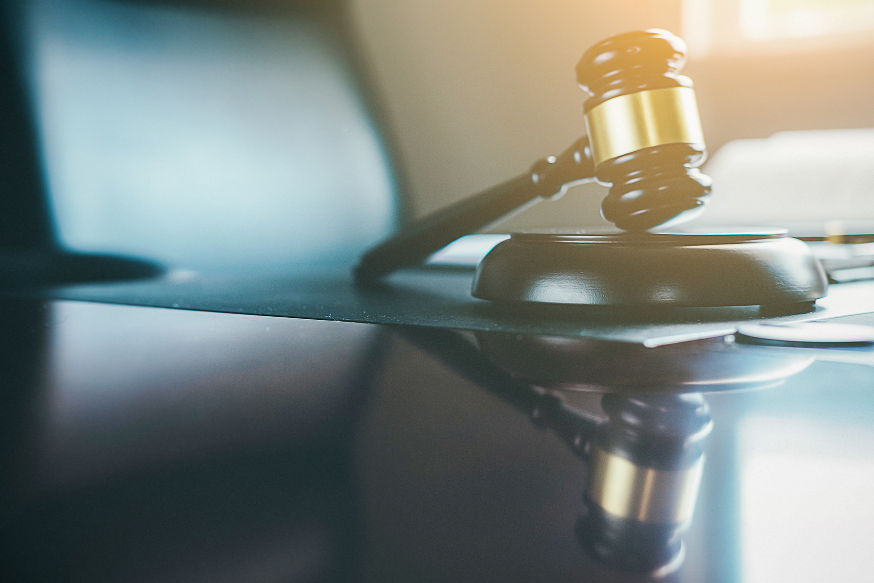 A gavel on a desk under a soft light, evoking the atmosphere of a courtroom or legal setting.