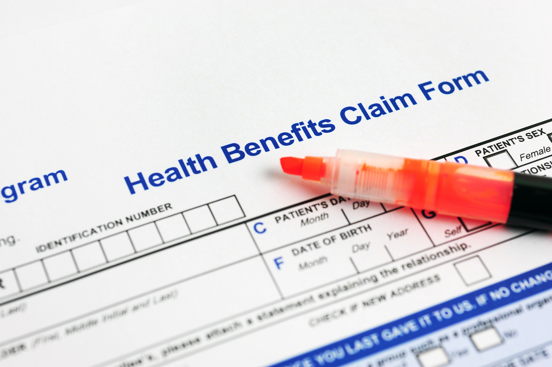 A health benefits claim form is partially filled out with a pen resting on top.