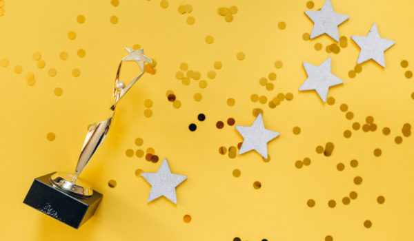 Golden statuette and stars on yellow background