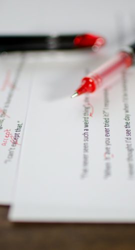 Red pen editing a manuscript