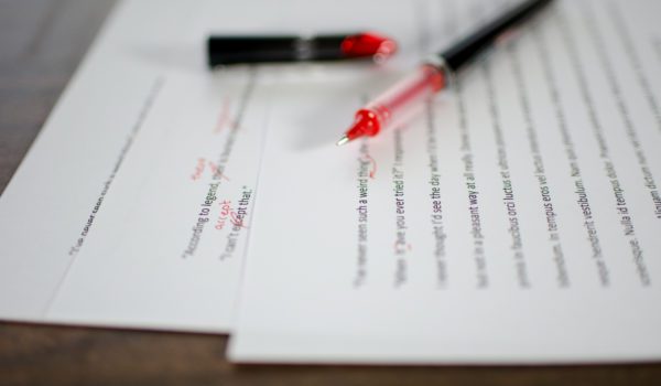 Red pen editing a manuscript