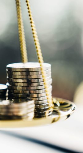 A balance scale is holding stacks of coins.