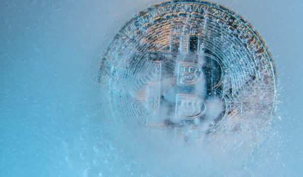 Prague, Czech Republic - October, 2019: Silver Bitcoin, bit coin online digital currency frozen in the blue ice. Concept of block chain, crypto market crash. Frozen crypto money, depreciation