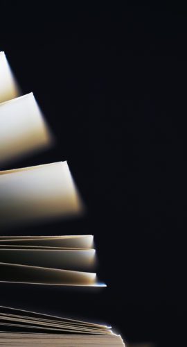 Macro view of book pages. Open book, white sheets on dark black background. Education background, copy space