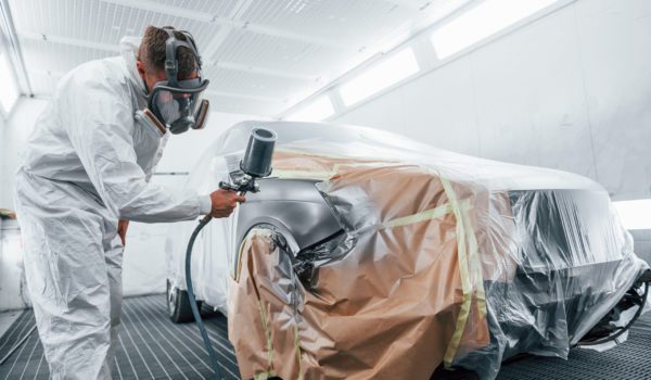 Professional painting a car in a paint booth