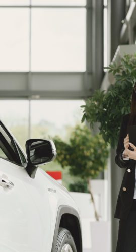 Employee of luxurious dealership standing in front of car
