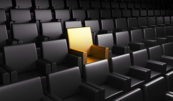 One golden seat in an empty auditorium surrounded by rows of black seats - QSBS Section 1202 Small Business Tax Exclusion