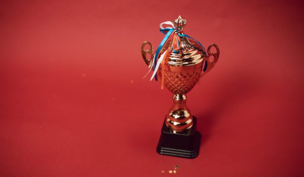 A trophy with tied ribbons on red background