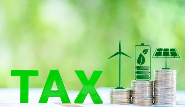 Clean, renewable energy or electricity production tax credits and incentives, financial concept : Green energy symbols atop coin stack e.g solar panel, wind turbine, fuel cell battery and the word TAX