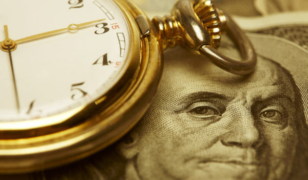 Macro shot of pocket watch face with 100 dollar bill Ben Franklin. Selective focus is on Franklin's Eyes. Gold Tone.