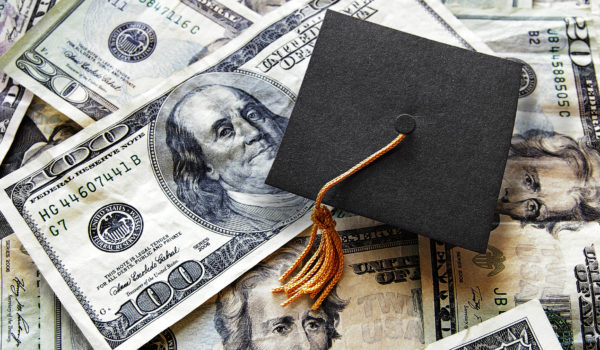 Miniature graduation cap on hundred dollar bills
