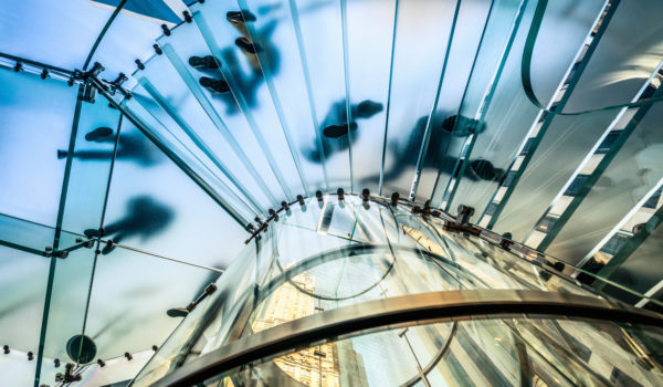"People walking on transparent glass spiral staircase in futuristic building, unrecognizable people."