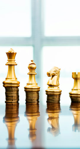 Chess pieces standing on the stacked coins.