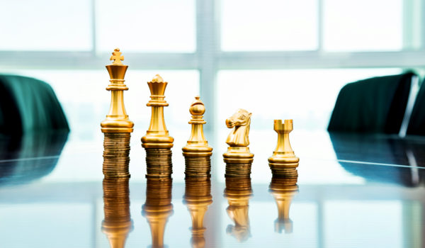 Chess pieces standing on the stacked coins.