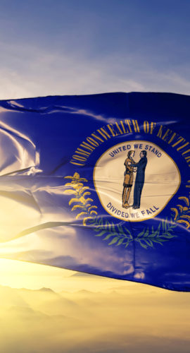 Kentucky state of United States flag on flagpole textile cloth fabric waving on the top sunrise mist fog