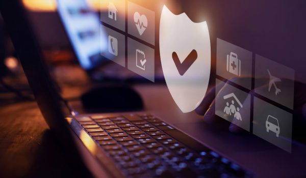 A laptop keyboard is shown with a digital overlay of security-related symbols, including a shield with a check mark.