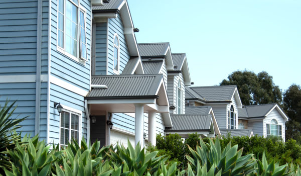 Frontal view of double-story townhouses characterized by their distinctive weatherboard wall cladding and corrugated metal roofs