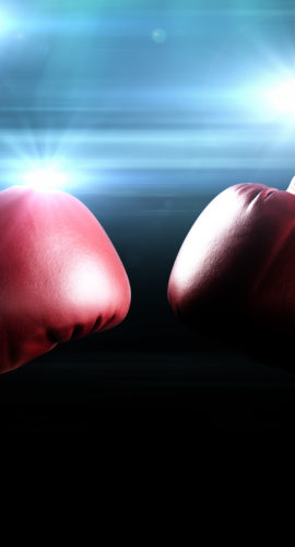 Red boxing gloves with the glow of flashes in the background.