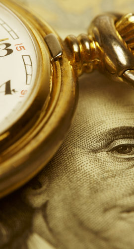 Macro shot of pocket watch face with 100 dollar bill Ben Franklin. Selective focus is on Franklin's Eyes. Gold Tone.