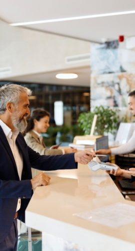 Modern man paying something with a credit card at the hotel reception