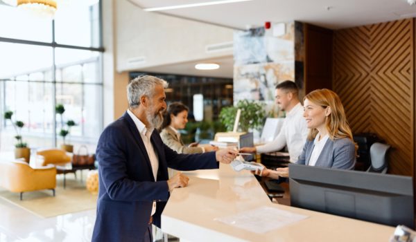 Modern man paying something with a credit card at the hotel reception